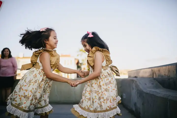 Twin girls dancing and laughing together outdoors